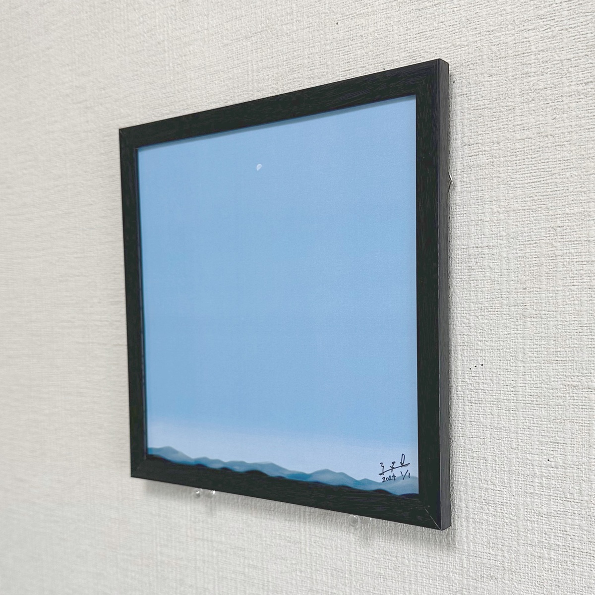 部屋に飾った一例です。額縁の裏には自立用の板と吊るための紐が付属していますので、お好みの場所で楽しんで頂けます。小さなサイズの作品ですが、絵の印象から、静かな場や落ち着いた雰囲気をもたらしてくれそうです ♪