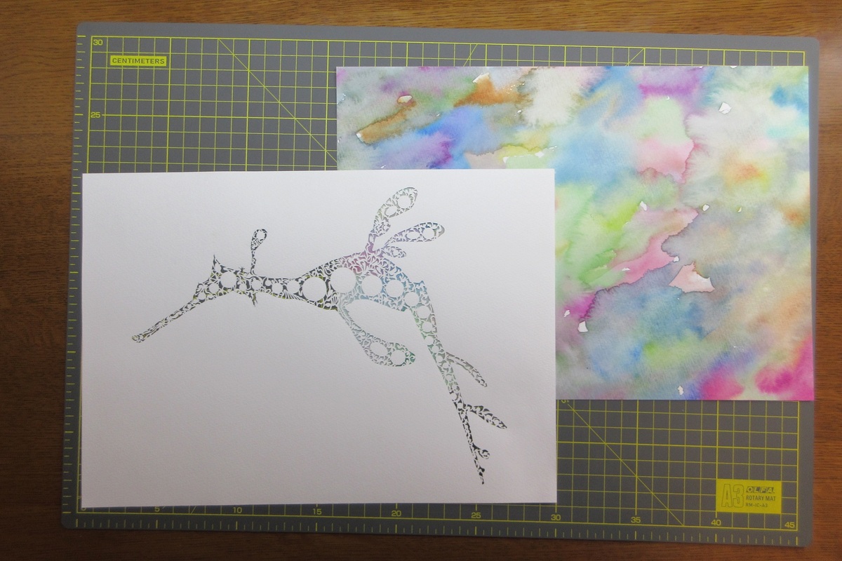 切り絵の下に透明水彩で着色した画用紙を敷いています。